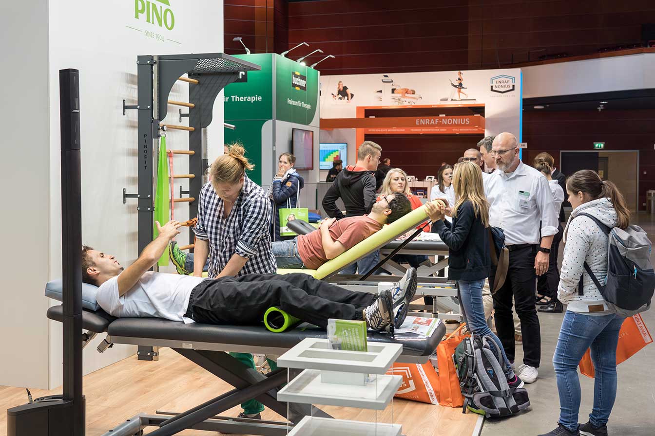 Besucher testen Therapieliegen an einem Stand auf der therapie, Fachmesse mit Kongress für Physiotherapie